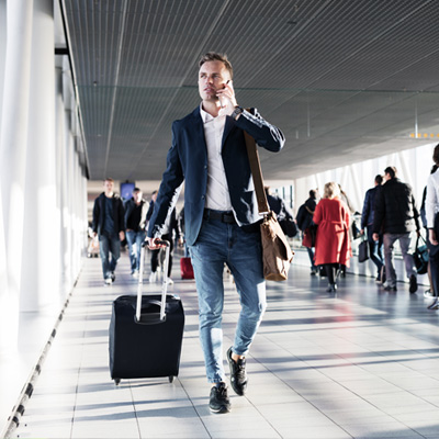 Mann mit Handgepäck und Handy am Flughafen